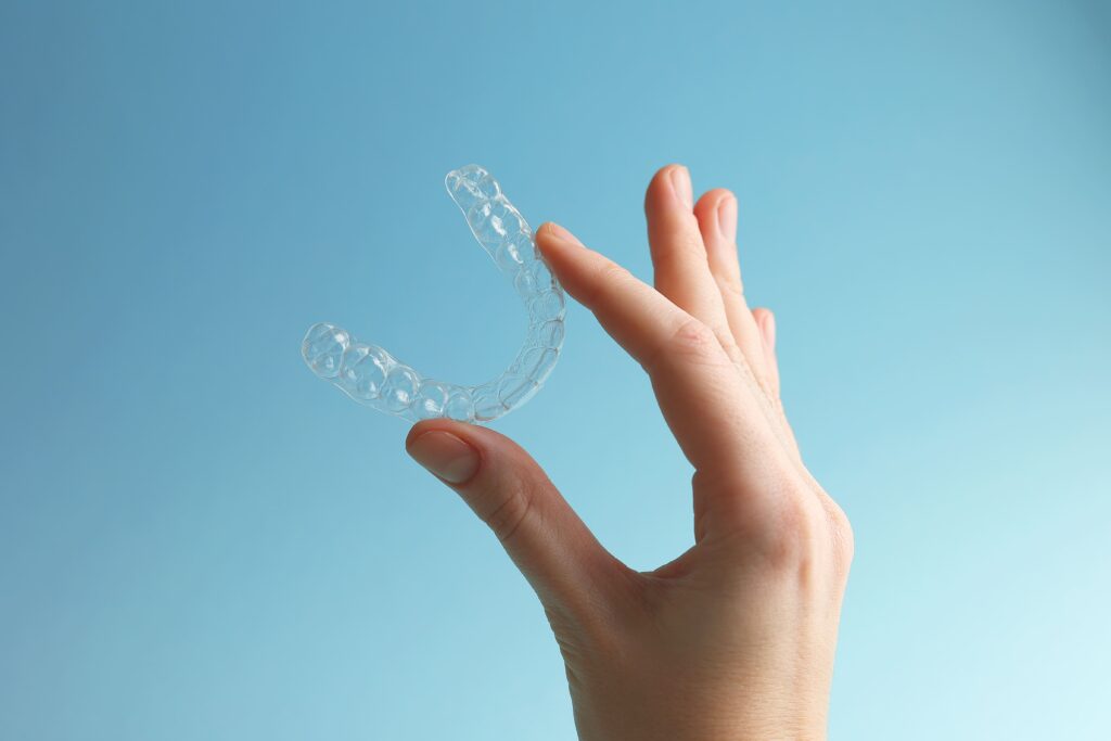 Mano que muestra unos alineadores transparentes para el tratamiento de ortodoncia invisible